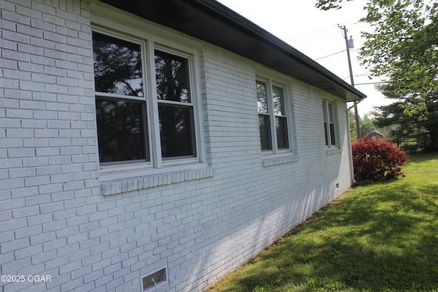 view of side of property featuring a lawn, crawl space, and brick siding