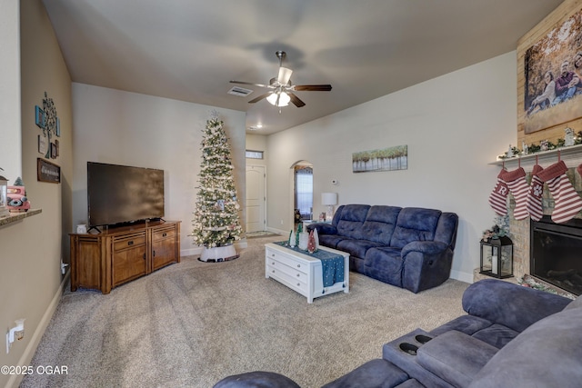 living room featuring ceiling fan, light colored carpet, and a large fireplace