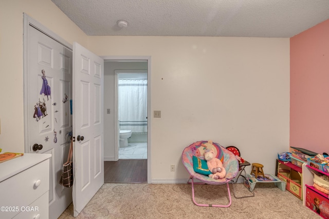 recreation room featuring a textured ceiling and light carpet