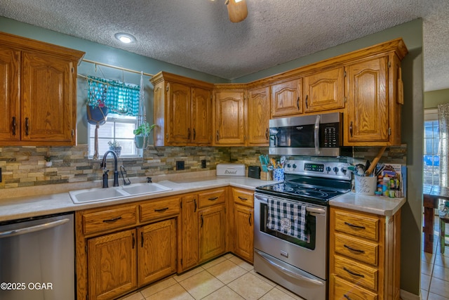 kitchen featuring a textured ceiling, appliances with stainless steel finishes, decorative backsplash, sink, and light tile patterned floors