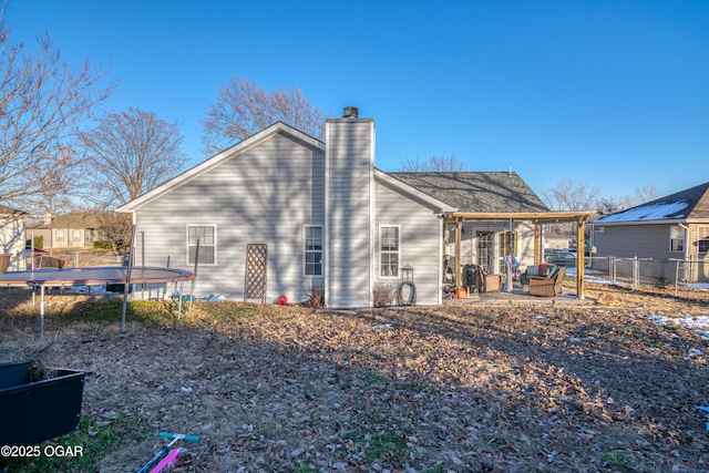 rear view of property with a trampoline and a patio area