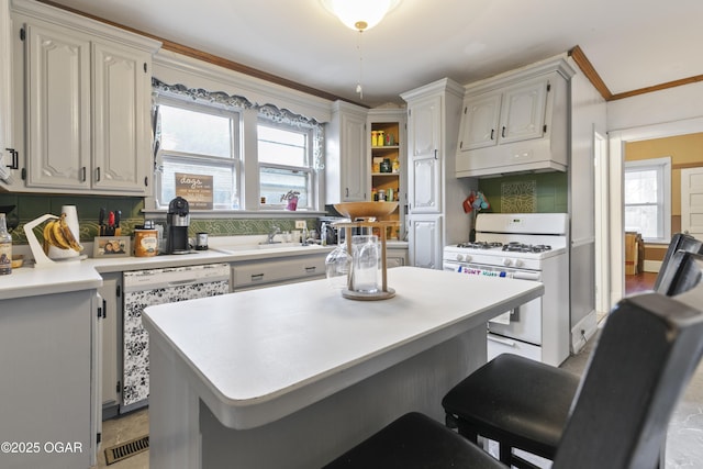 kitchen featuring a kitchen bar, sink, white appliances, and white cabinets