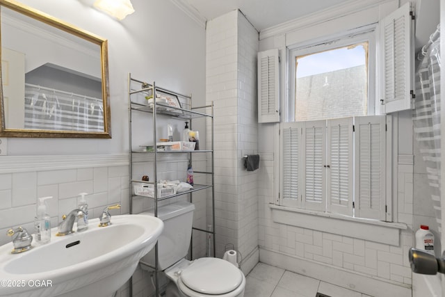 bathroom featuring toilet, tile walls, tile patterned floors, sink, and crown molding