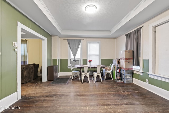 dining space featuring dark wood-type flooring, ornamental molding, and a raised ceiling