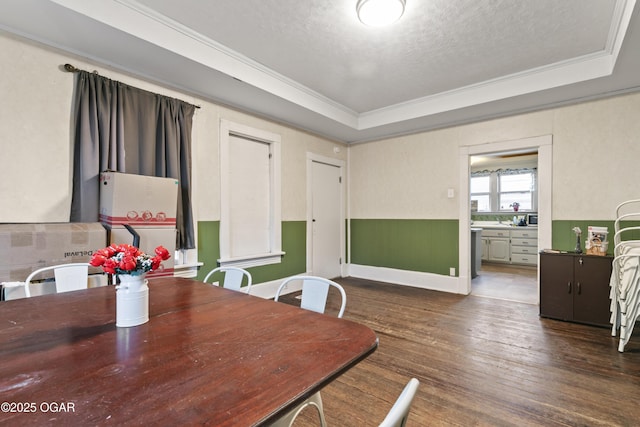 dining room featuring crown molding, dark hardwood / wood-style flooring, a tray ceiling, and a textured ceiling