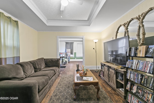 living room featuring ceiling fan, a healthy amount of sunlight, dark hardwood / wood-style floors, a tray ceiling, and ornamental molding