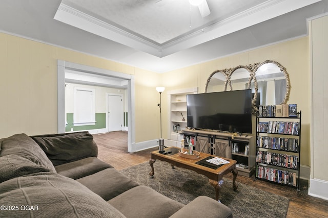 living room featuring ceiling fan, dark hardwood / wood-style flooring, ornamental molding, and a tray ceiling