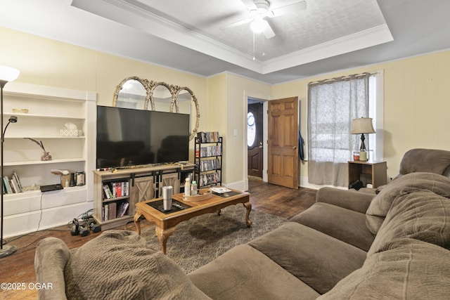 living room featuring ceiling fan, dark hardwood / wood-style flooring, ornamental molding, and a raised ceiling