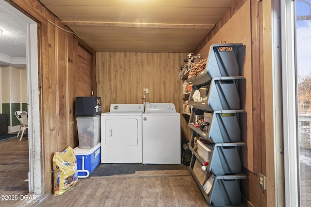 clothes washing area featuring washer and dryer, dark hardwood / wood-style flooring, and wooden walls