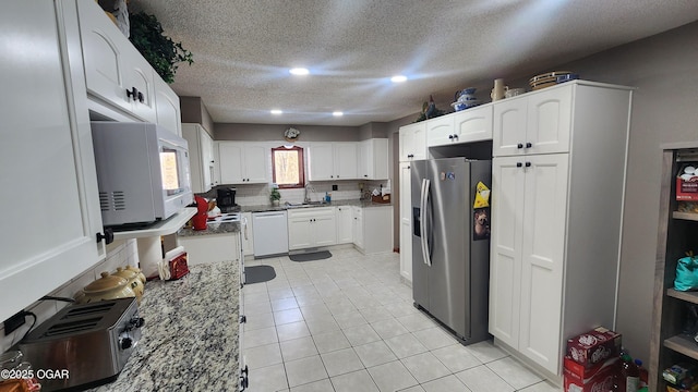 kitchen with light stone countertops, white appliances, white cabinetry, backsplash, and light tile patterned floors