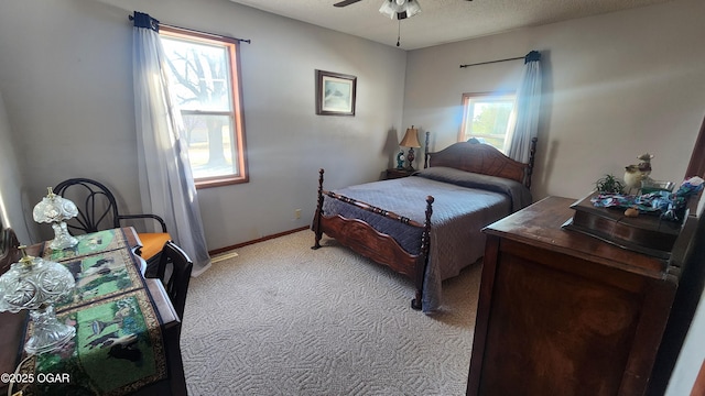 bedroom featuring ceiling fan, light carpet, multiple windows, and a textured ceiling