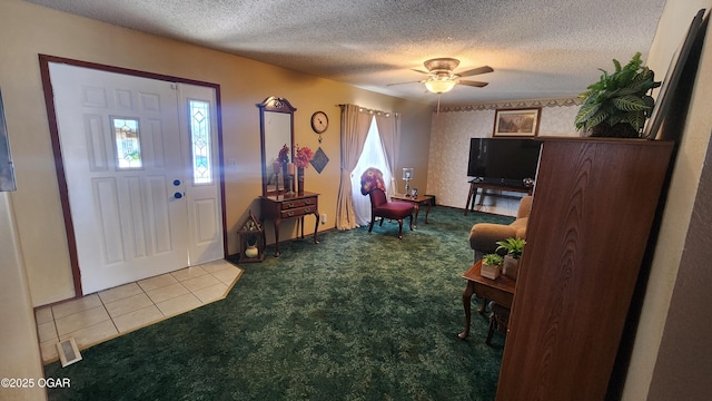 tiled foyer with ceiling fan, a healthy amount of sunlight, and a textured ceiling