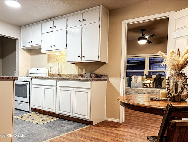 kitchen featuring a textured ceiling, white range with gas cooktop, ceiling fan, light hardwood / wood-style floors, and white cabinets