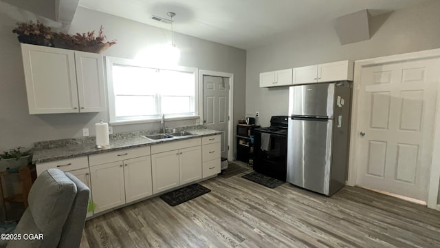 kitchen featuring stainless steel refrigerator, black range with electric cooktop, pendant lighting, white cabinets, and sink