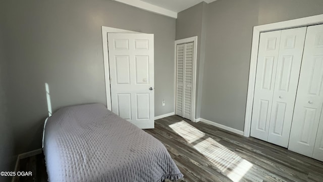 bedroom with dark hardwood / wood-style flooring and multiple closets