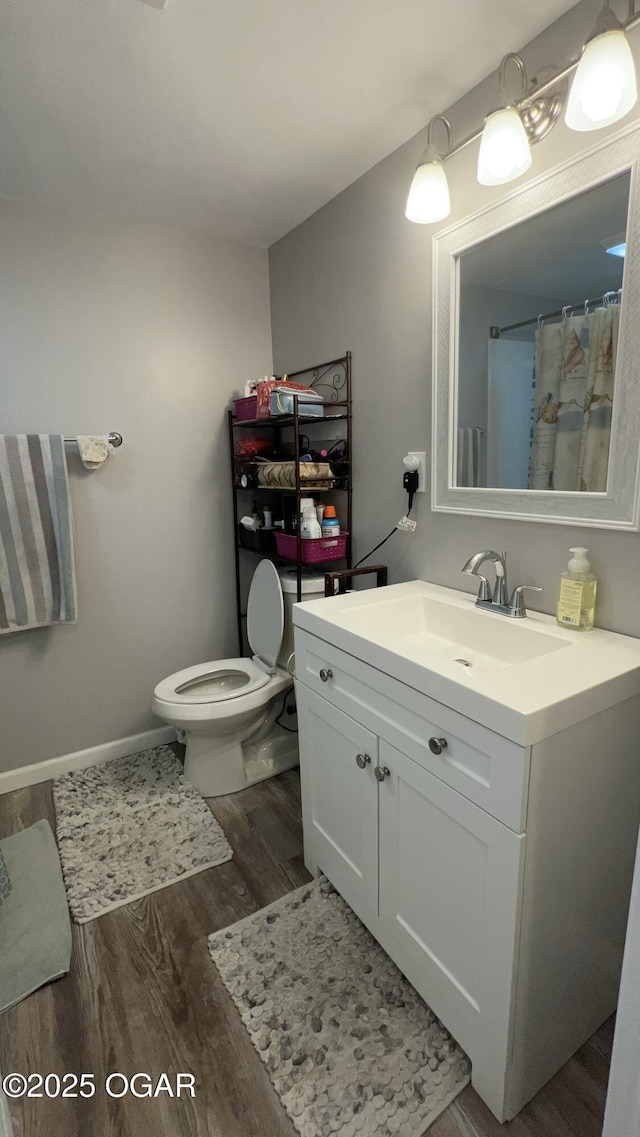 bathroom with toilet, hardwood / wood-style flooring, vanity, and curtained shower