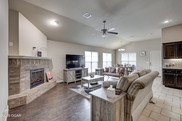 living room featuring ceiling fan, vaulted ceiling, a brick fireplace, and light wood-type flooring