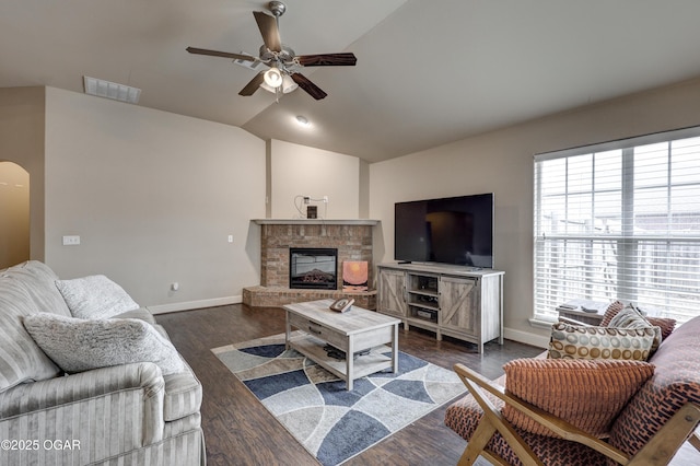 living room featuring vaulted ceiling, dark wood-type flooring, a fireplace, and ceiling fan