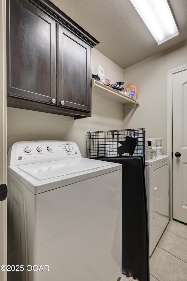 washroom with washer and clothes dryer, light tile patterned floors, and cabinets