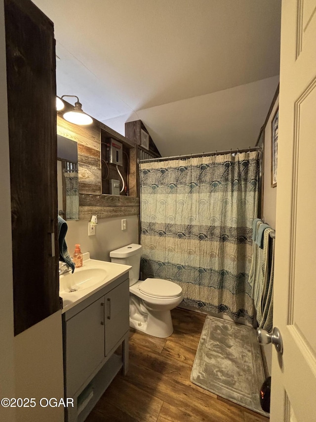 bathroom featuring toilet, wood-type flooring, walk in shower, vanity, and vaulted ceiling