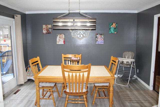 dining area with hardwood / wood-style floors and ornamental molding