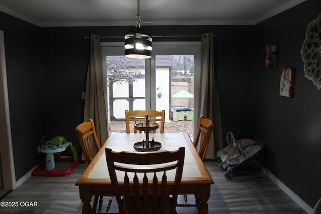 dining area featuring wood-type flooring and crown molding