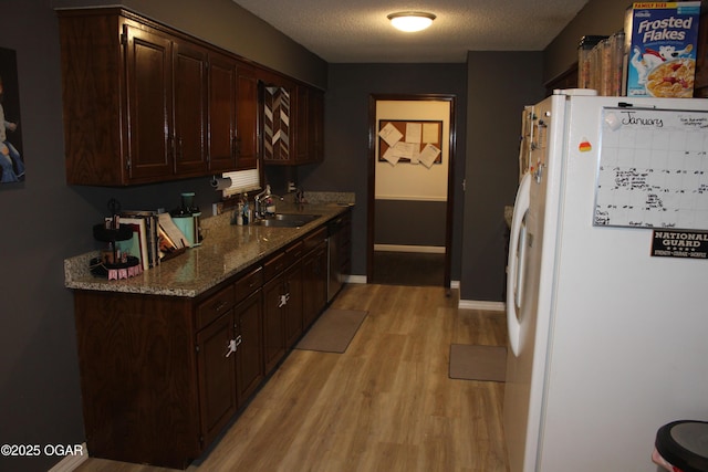 kitchen with light hardwood / wood-style floors, dark brown cabinets, a textured ceiling, white refrigerator, and sink