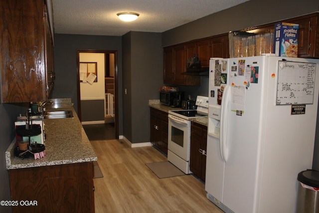 kitchen featuring light stone countertops, white appliances, a textured ceiling, sink, and light wood-type flooring