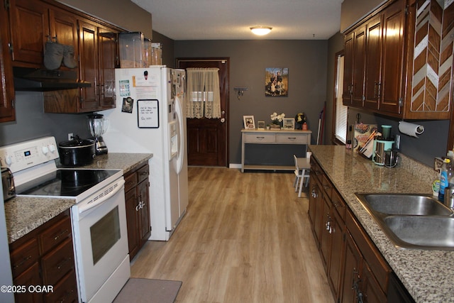 kitchen with sink, white appliances, stone countertops, and light hardwood / wood-style flooring