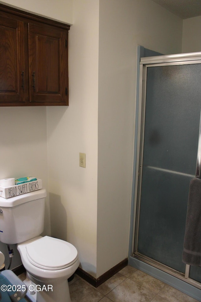 bathroom featuring toilet, tile patterned floors, and a shower with door