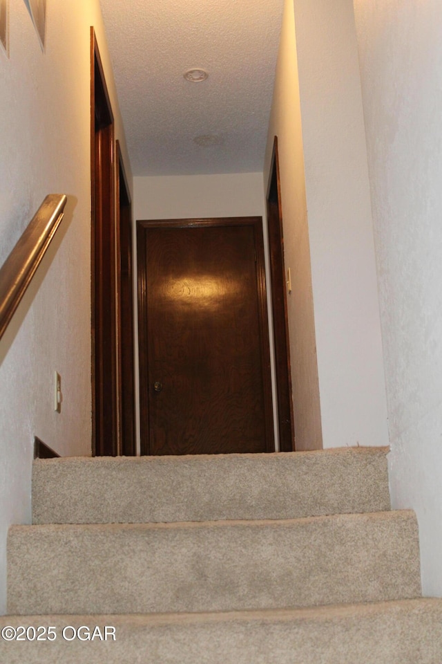 staircase with a textured ceiling