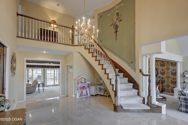 stairs featuring an inviting chandelier, a towering ceiling, and decorative columns