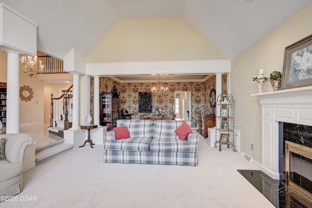 living room featuring an inviting chandelier, carpet floors, a premium fireplace, and decorative columns