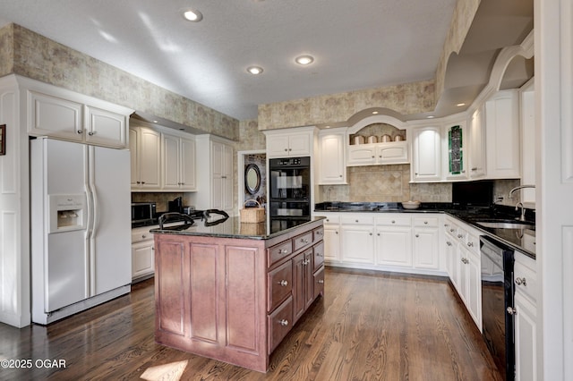 kitchen featuring sink, dark wood-type flooring, white cabinetry, black appliances, and an island with sink