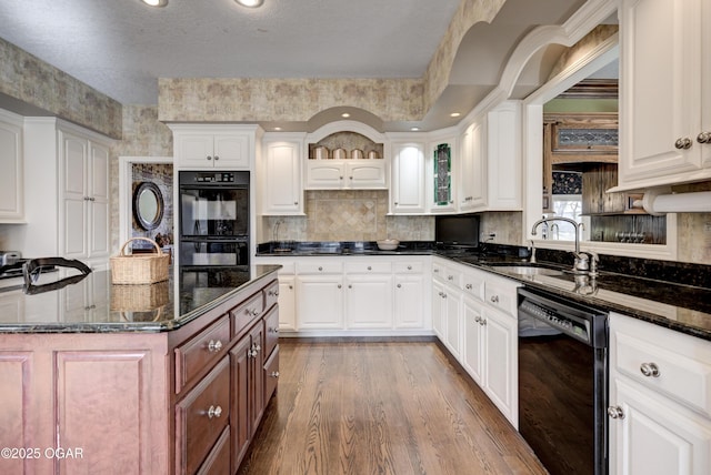 kitchen with a spacious island, white cabinets, dark stone counters, and black appliances