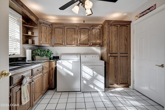 clothes washing area featuring washer and dryer, light tile patterned floors, sink, and cabinets