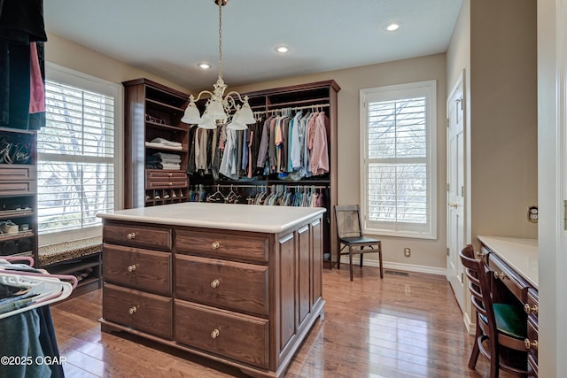 spacious closet with a notable chandelier and hardwood / wood-style flooring