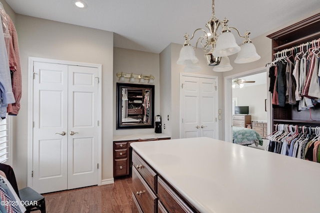 walk in closet with an inviting chandelier and hardwood / wood-style floors