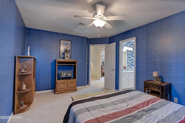 carpeted bedroom featuring ceiling fan, sink, ensuite bath, and a textured ceiling