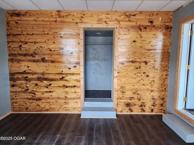 spare room with dark wood-type flooring and wood walls