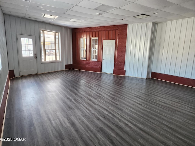 spare room featuring a paneled ceiling and wooden walls