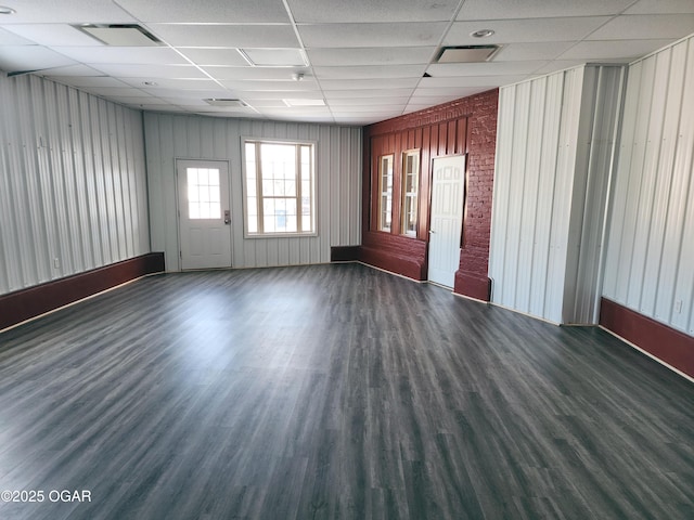 spare room with a drop ceiling and dark hardwood / wood-style flooring