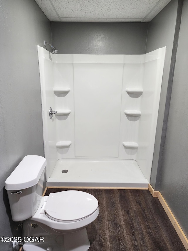 bathroom featuring hardwood / wood-style flooring, toilet, walk in shower, and a paneled ceiling