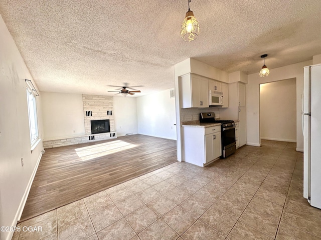 kitchen featuring white cabinetry, a tiled fireplace, hanging light fixtures, and white appliances