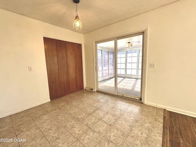 unfurnished bedroom with access to exterior, a textured ceiling, a closet, and tile patterned flooring