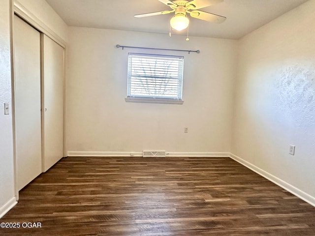 unfurnished bedroom featuring dark wood-type flooring, ceiling fan, and a closet