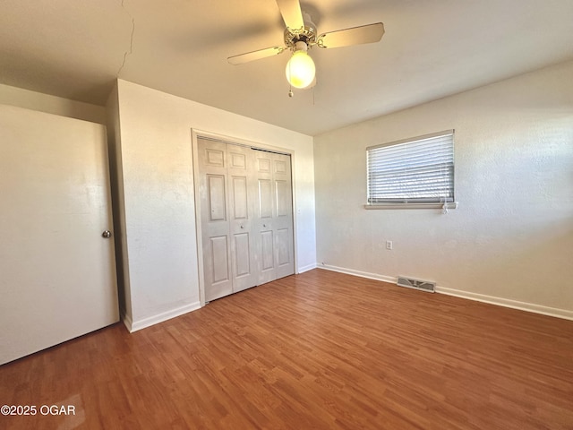 unfurnished bedroom with ceiling fan, a closet, and hardwood / wood-style floors