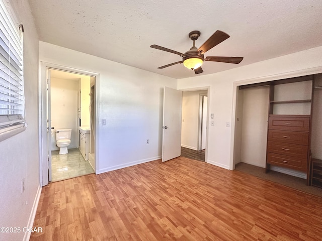 unfurnished bedroom with a textured ceiling, connected bathroom, a closet, ceiling fan, and light hardwood / wood-style flooring