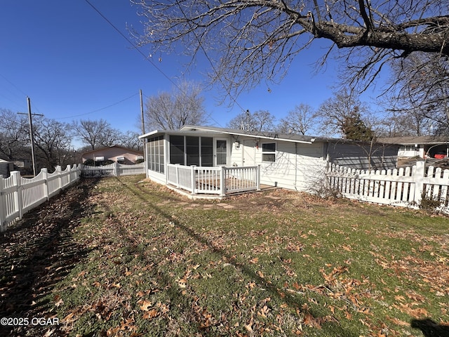 back of property with a sunroom and a lawn