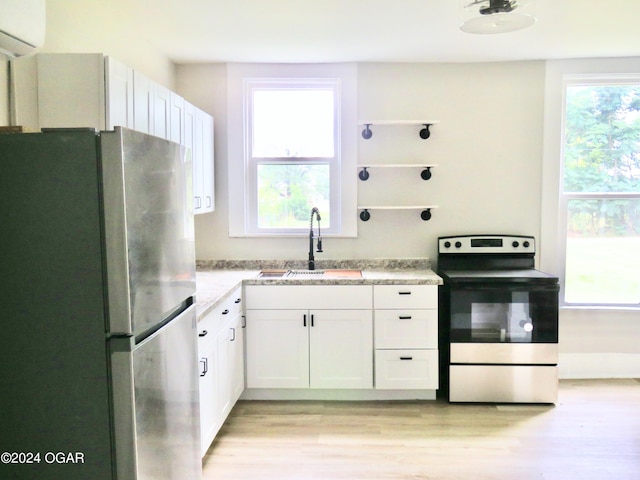 kitchen with light hardwood / wood-style floors, stainless steel appliances, a wall mounted air conditioner, white cabinets, and sink